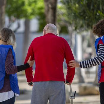 Hombres ayudando a un anciano a andar